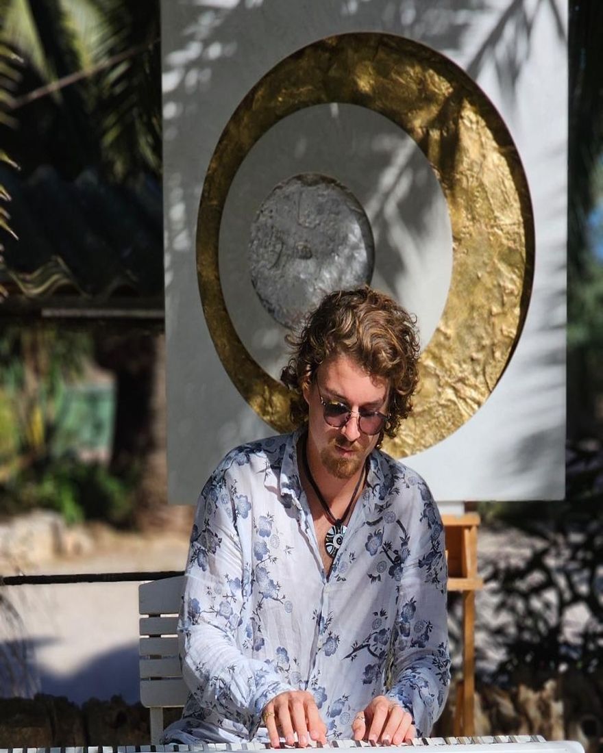 Jonas Borchert am Klavier vor einem goldenen Gong